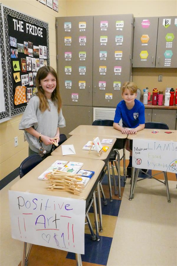two students at desk with signs